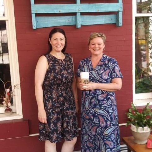 Two women stand in front of Hope and Coffee sign